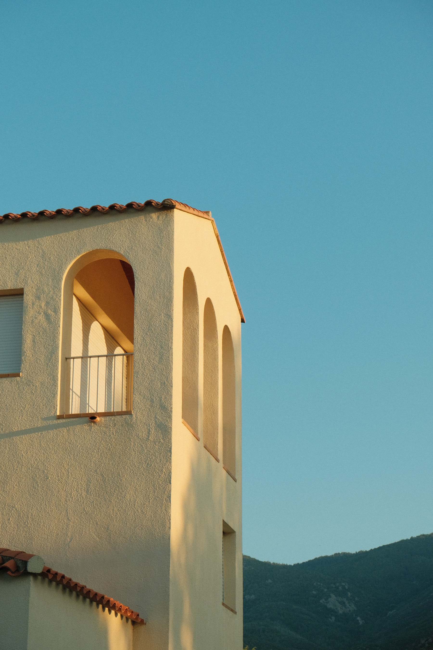 A white stucco tower with an arched loggia catches the last warm light in Laroque-des-Albères, a village at the foot of the Albères in the eastern Pyrenees, with the hills behind
